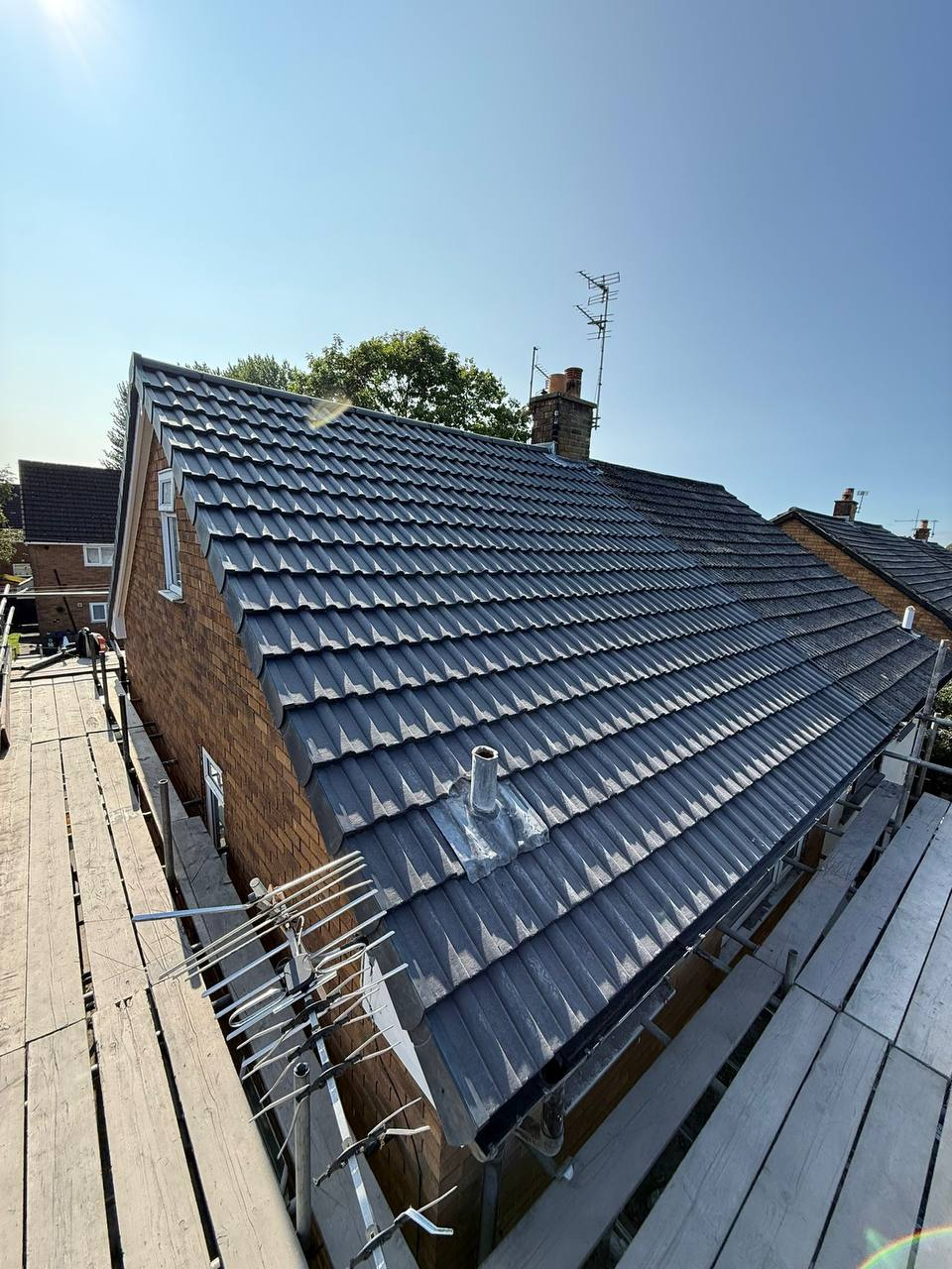 Dark grey tiled hipped roof completed with scaffolding
