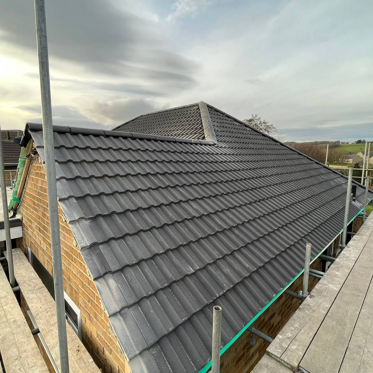 Grey tiled hipped roof completed with scaffolding
